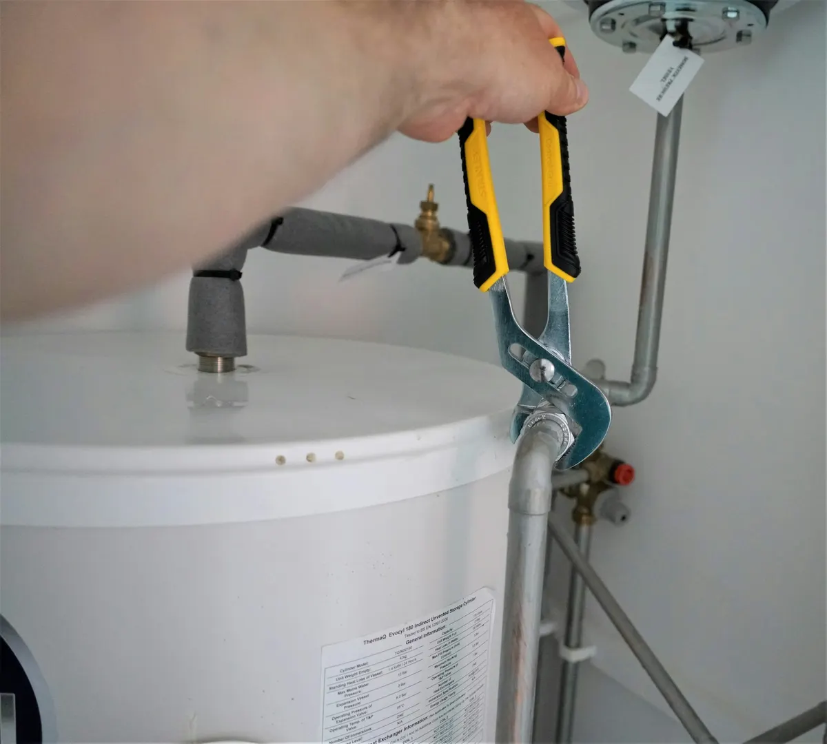 Installateur zieht eine Verschraubung am Warmwasserspeicher fest