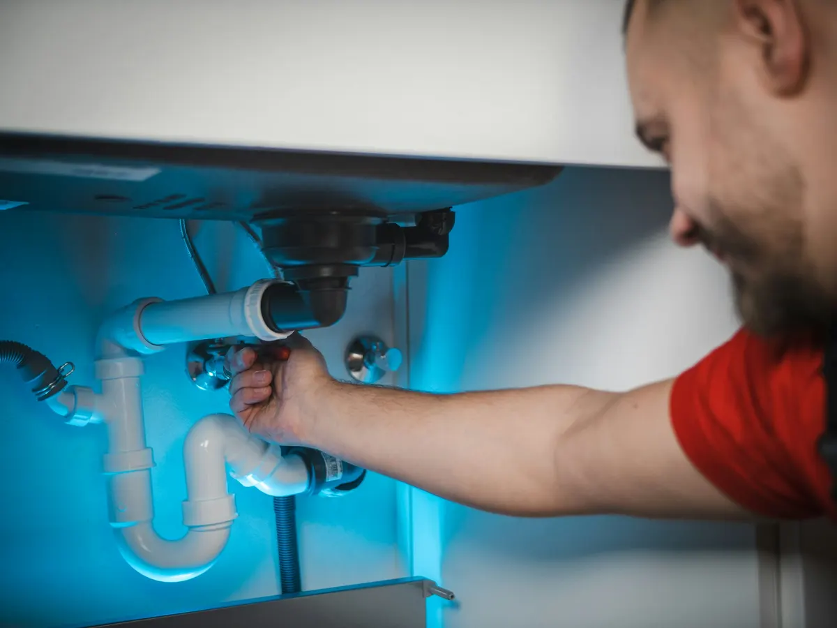 Installateur montiert einen Siphon unter einem Waschbecken